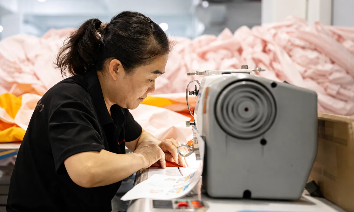Worker double-stitching commercial inflatable panels on an industrial sewing machine