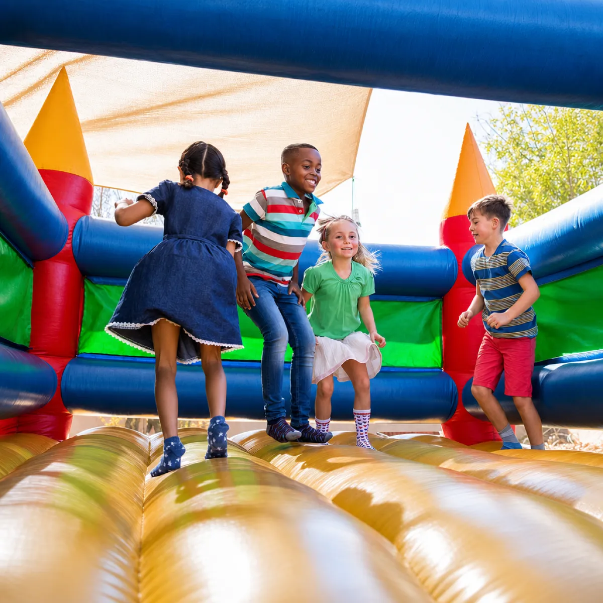 Commercial bounce house set up at an outdoor rental event with blower and anchor stakes visible