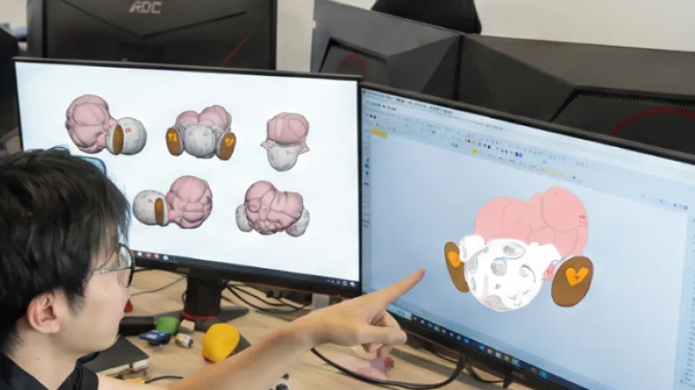 Designer 3D modeling a custom inflatable character on dual monitors