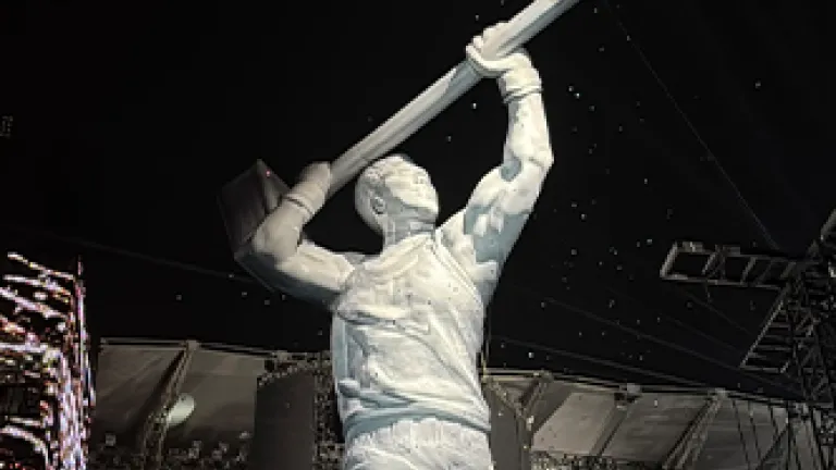 Giant white performer figure inflatable on concert stage at night