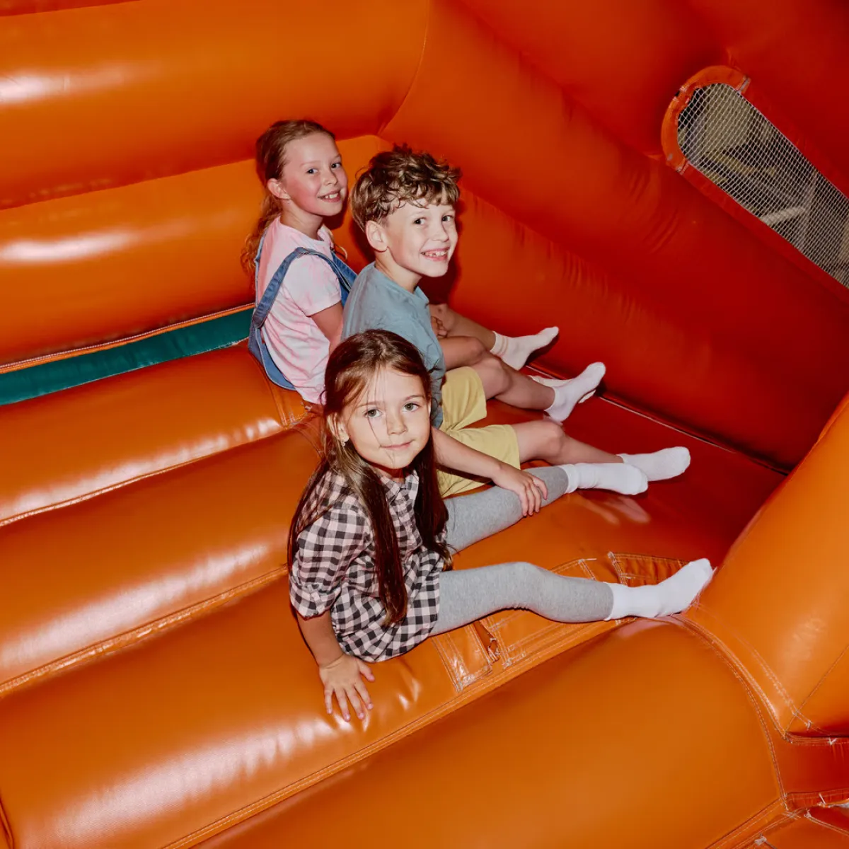 Commercial combo bounce house with slide set up for a backyard birthday party, blower and anchor stakes visible