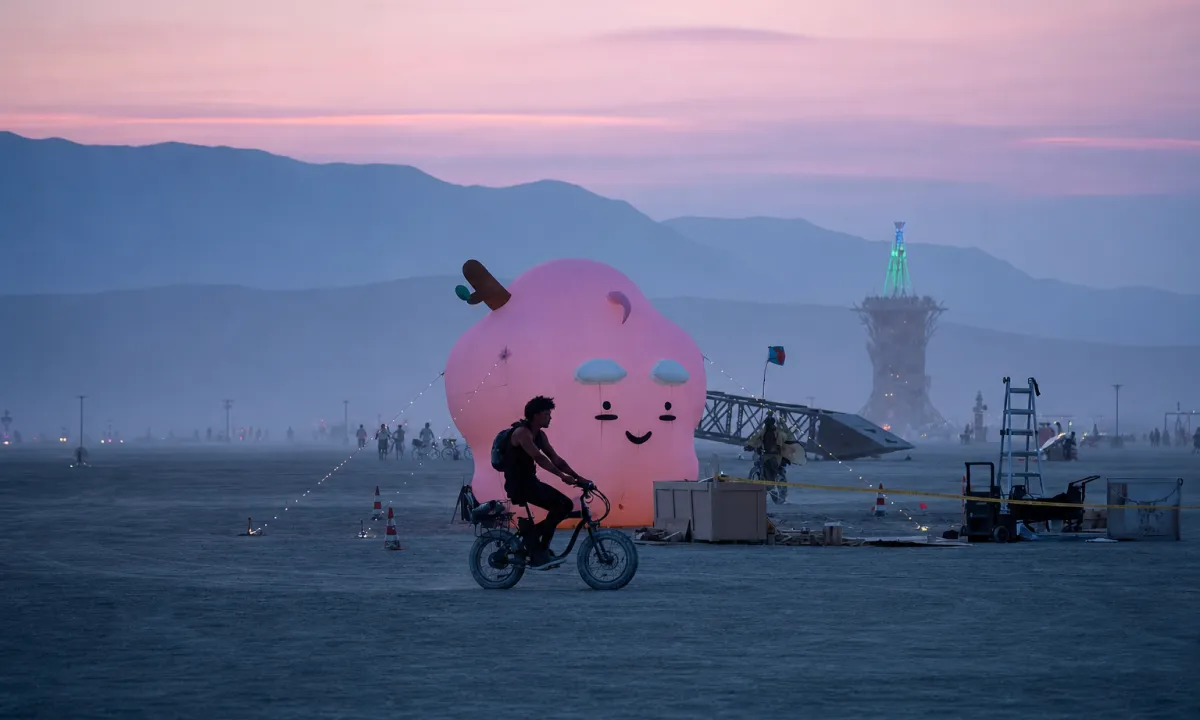 Giant pink EMO inflatable art installation at sunset on the playa